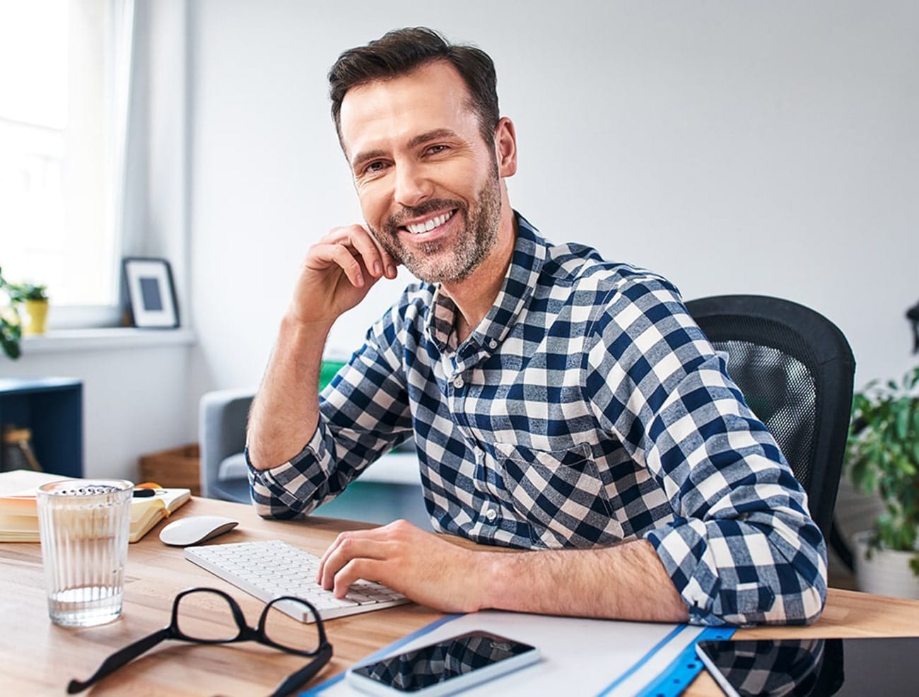 man sitting an desk, smiling thankful for TMJ solutions