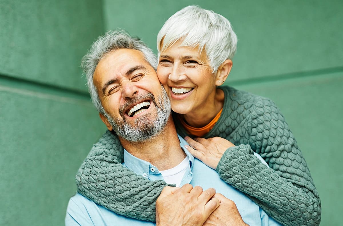 mature couple smiling with natural tooth replacement options, dental bridges